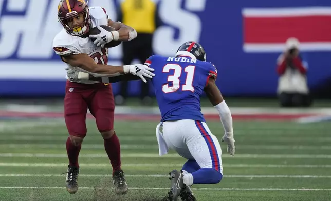 Washington Commanders running back Austin Ekeler (30) avoids a tackle by New York Giants safety Tyler Nubin (31) during the fourth quarter of an NFL football game, Sunday, Nov. 3, 2024, in East Rutherford, N.J. (AP Photo/Seth Wenig)