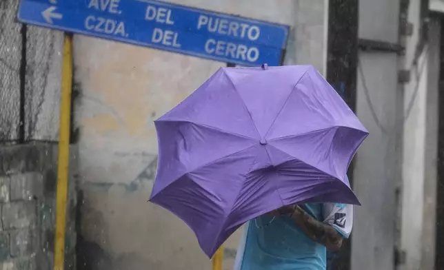 A man walks through the wind and rain brought by Hurricane Rafael in Havana, Cuba, Wednesday, Nov. 6, 2024. (AP Photo/Ramon Espinosa)