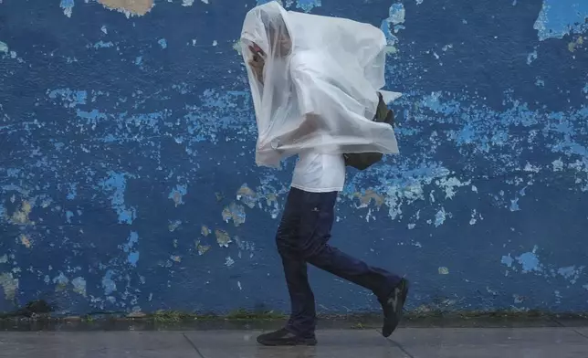 A man walks through the wind and rain brought by Hurricane Rafael in Havana, Cuba, Wednesday, Nov. 6, 2024. (AP Photo/Ramon Espinosa)