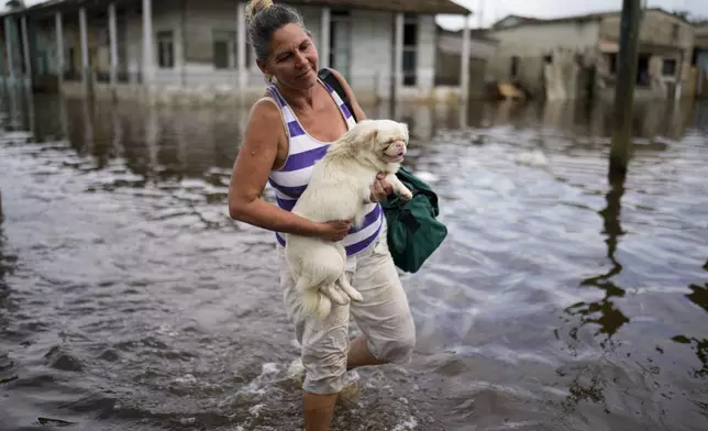 Madeleine Mur carries her dog through a flooded street after Hurricane Rafael passed through Batabano, Cuba, Thursday, Nov. 7, 2024. (AP Photo/Ramon Espinosa)