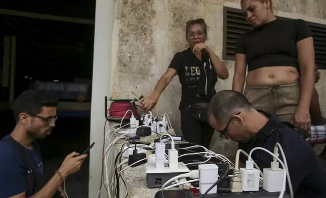 Residents charge their devices after Hurricane Rafael caused partial outages throughout Havana, Cuba Thursday, Nov. 7, 2024. (AP Photo/Ariel Ley)