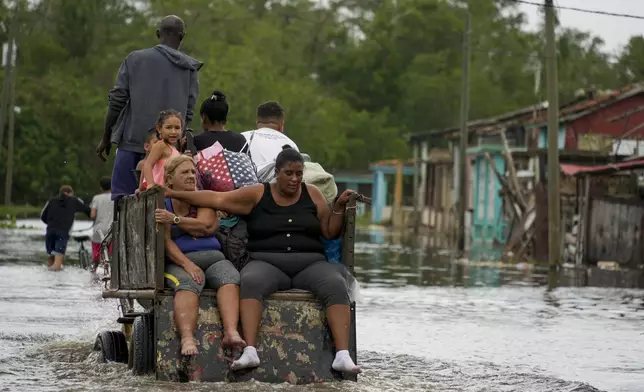 Residents ride through a flooded street on a horse-drawn cart after Hurricane Rafael passed through Batano, Cuba, Thursday, Nov. 7, 2024. (AP Photo/Ramon Espinosa)