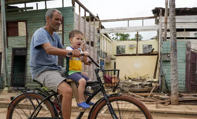 Residents cycle past homes damaged when Hurricane Rafael passed through Batabano, Cuba, Thursday, Nov. 7, 2024. (AP Photo/Ramon Espinosa)