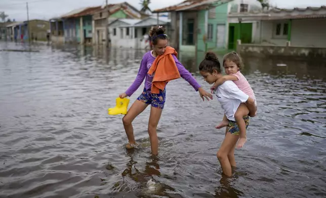 Children wade through a flooded street after the passing of Hurricane Rafael in Batabano, Cuba, Thursday, Nov. 7, 2024. (AP Photo/Ramon Espinosa)