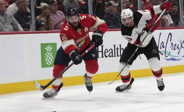 Florida Panthers defenseman Aaron Ekblad (5) and New Jersey Devils right wing Stefan Noesen (11) go for the puck during the first period of an NHL hockey game, Tuesday, Nov. 12, 2024, in Sunrise, Fla. (AP Photo/Lynne Sladky)