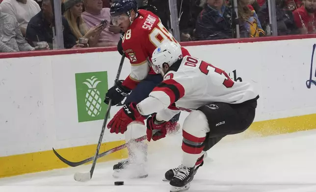 Florida Panthers defenseman Nate Schmidt (88) and New Jersey Devils center Justin Dowling, right, go for the puck during the first period of an NHL hockey game, Tuesday, Nov. 12, 2024, in Sunrise, Fla. (AP Photo/Lynne Sladky)