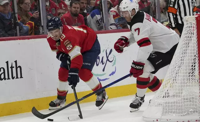 Florida Panthers left wing Matthew Tkachuk (19) and New Jersey Devils defenseman Dougie Hamilton (7) go for the puck during the second period of an NHL hockey game, Tuesday, Nov. 12, 2024, in Sunrise, Fla. (AP Photo/Lynne Sladky)