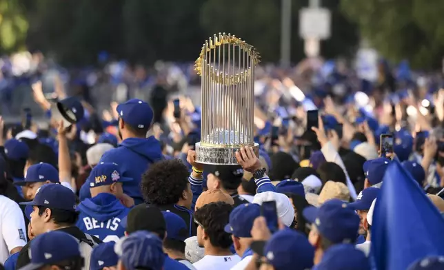 A fan holds a replica trophy during the Los Angeles Dodgers baseball World Series championship parade Friday, Nov. 1, 2024, in Los Angeles. (AP Photo/Kyusung Gong)