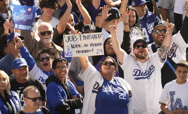 Fans cheer and hold signs before the Los Angeles Dodgers baseball World Series championship parade Friday, Nov. 1, 2024, in Los Angeles. (AP Photo/Damian Dovarganes)