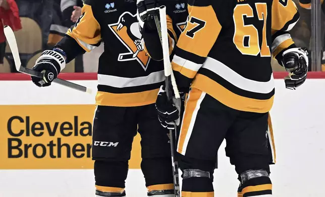 Pittsburgh Penguins' Matt Grzelcyk (24) and Rickard Rakell (67) celebrate with Sidney Crosby after Crosby's game tying goal against the Anaheim Ducks in the third period of an NHL hockey game Thursday Oct. 31, 2024 in Pittsburgh. (Chaz Palla/Pittsburgh Tribune-Review via AP)