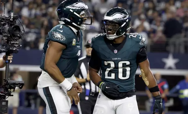 Philadelphia Eagles' Jalen Hurts, left, and Saquon Barkley (26) celebrate after Hurts ran the ball for a touchdown in the second half of an NFL football game in Arlington, Texas, Sunday, Nov. 10, 2024. (AP Photo/Gareth Patterson)