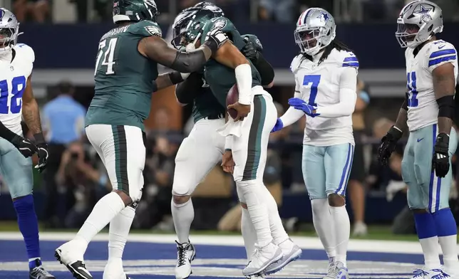 Philadelphia Eagles' Fred Johnson, left, and Lane Johnson, rear, celebrate with Jalen Hurts, center, after Hurts ran for a touchdown as Dallas Cowboys' Trevon Diggs (7) and Micah Parsons (11) look on in the second half of an NFL football game in Arlington, Texas, Sunday, Nov. 10, 2024. (AP Photo/Jeffrey McWhorter)