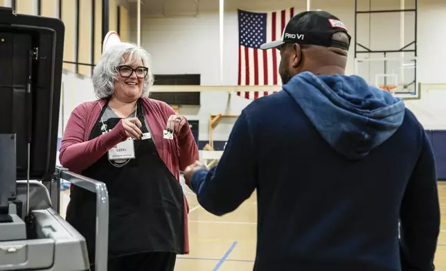 Poll worker Kerri Ryan gives a choice of "I voted" stickers to Sasha Dix after he submitted his ballot at TC Roberson High School on Election Day, Tuesday, Nov. 5, 2024 in Asheville, N.C. (AP Photo/Kathy Kmonicek)