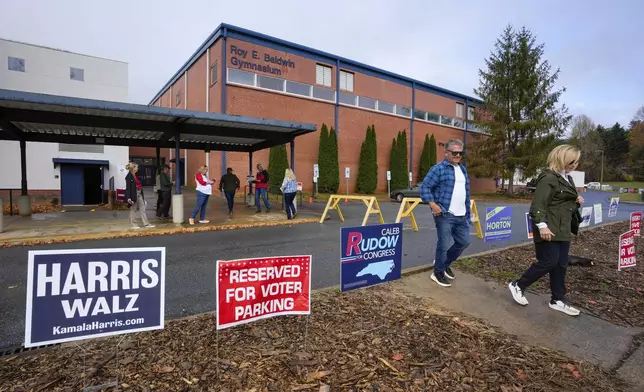 Voters walk through rows of political signs outside of TC Roberson High School on Election Day, Tuesday, Nov. 5, 2024 in Asheville, N.C. (AP Photo/Kathy Kmonicek)