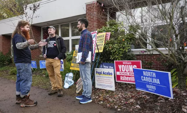 University of North Carolina at Asheville student, Elijah Walker-Haigh, left, speaks with advocates for Vice President Kamala Harris, Greg Horwitch, middle, and David Dean outside the West Asheville Public Library on Election Day, Tuesday, Nov. 5, 2024 in Asheville, N.C. (AP Photo/Kathy Kmonicek)