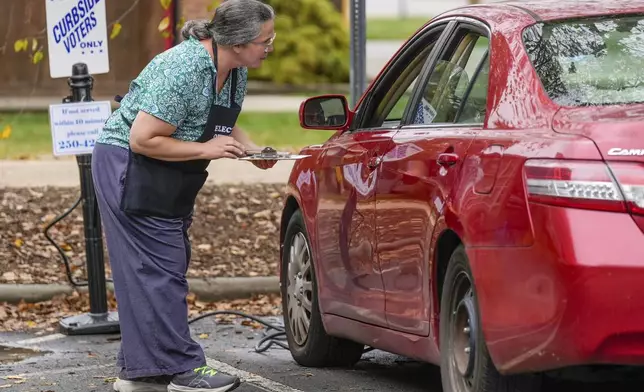 Poll worker, Genevieve Bieniosek helps a voter with curbside voting outside the West Asheville Public Library on Election Day, Tuesday, Nov. 5, 2024 in Asheville, N.C. (AP Photo/Kathy Kmonicek)