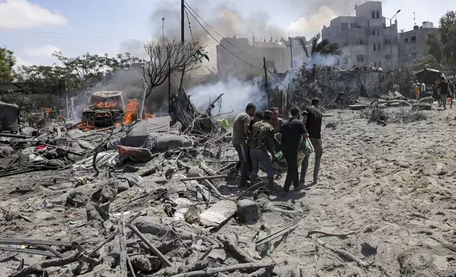 FILE - Palestinians evacuate a body from a site hit by an Israeli bombardment on Khan Younis, southern Gaza Strip, Saturday, July 13, 2024. (AP Photo/Jehad Alshrafi, File)