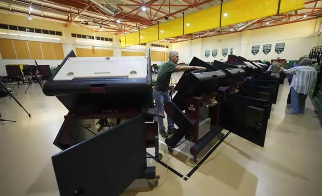 John Farnsworth sets up voting machines at the Hynes Charter School in New Orleans on Election Day, Tuesday, Nov. 5, 2024. (AP Photo/Gerald Herbert)