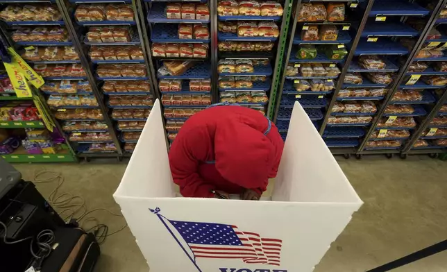 A woman votes at a grocery store on Election Day, Tuesday, Nov. 5, 2024, in Lawrence, Kan. (AP Photo/Charlie Riedel)