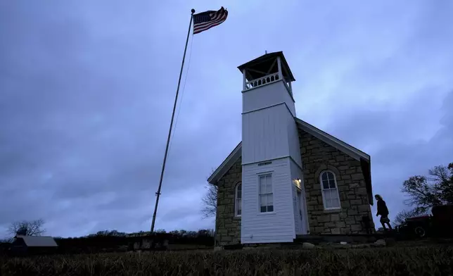 A voter arrives at the 146-year-old Buck Creek school to cast their ballot on Election Day, Tuesday, Nov. 5, 2024, in rural Perry, Kan. (AP Photo/Charlie Riedel)