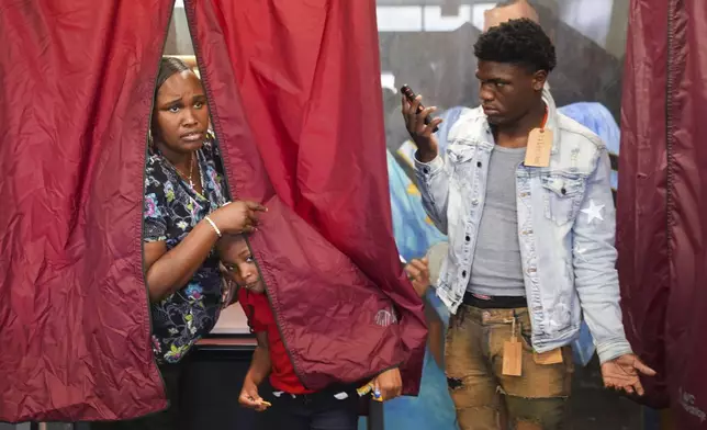 Kendra Franklin looks for assistance as she votes with her children, Mi'Kayla and Kendall, right, at a campus polling place at Southern University, an HBCU, in Baton Rouge, La., on Election Day, Tuesday, Nov. 5, 2024. (AP Photo/Gerald Herbert)