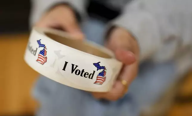 A poll worker holds a roll of "I Voted" stickers at a polling place, Tuesday, Nov. 5, 2024, in Dearborn, Mich. (AP Photo/Charlie Neibergall)