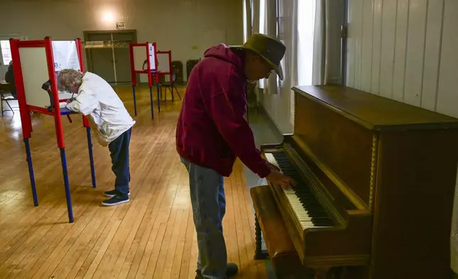 Charles Cunningham plays the piano as his mother Pearl votes at Drummond Community Hall in Drummond, Mont., on Election Day, Tuesday, Nov. 5, 2024. (AP Photo/Tommy Martino)