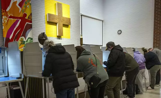 Chris McCollister, left, votes at a voting booth along with others in her district on Election Day Tuesday, Nov. 5, 2024, at Redeemer Lutheran Church in Lincoln, Neb. (Kenneth Ferriera/Lincoln Journal Star via AP)