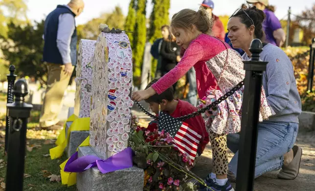 Ellen Gardiner, 6, leaves an "I voted" sticker on the headstone of Susan B. Anthony at Mount Hope Cemetery in Rochester, New York on Election Day, Tuesday, Nov. 5, 2024. (AP Photo/Lauren Petracca)