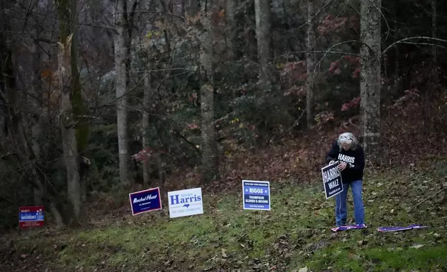 A campaign worker posts a Harris-Walz sign near a polling place, Tuesday, Nov. 5, 2024, in Black Mountain, N.C. (AP Photo/George Walker IV)