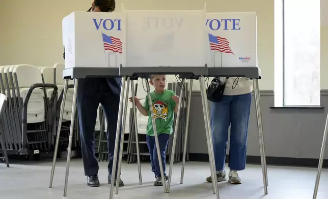 Four-year-old Stone Smathers, center, waits for his parents to finish voting, Tuesday, Nov. 5, 2024, in Canton, N.C. (AP Photo/George Walker IV)