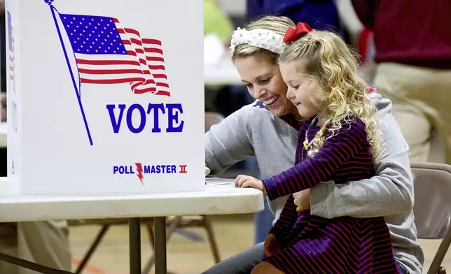 Kate Aurandt-Gribbler holds her daughter, Olivia Gribbler, 3, as she votes at the Westmont Borough No. 1 polling place at Westmont Grove in Johnstown, Pa., in Cambria County, on Tuesday, Nov. 5, 2024. (Thomas Slusser/The Tribune-Democrat via AP)