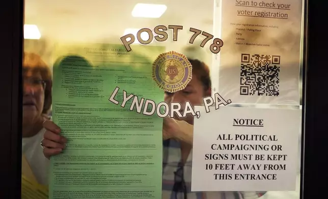 Officials post notices before opening the doors to voters at American Legion Post 778 in Butler Township, Pa., on Election Day, Tuesday, Nov. 5, 2024. (AP Photo/Robert F. Bukaty)