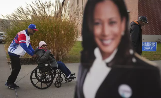 Liza Fortt, 74, center, accompanied by her son Timothy Walker, left, and husband Willie Fortt moves in line to cast her ballot for Democratic presidential nominee Vice President Kamala Harris at a polling place at Scranton High School in Scranton, Pa., on Election Day, Tuesday, Nov. 5, 2024. (AP Photo/Matt Rourke)