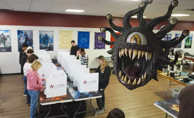 Beholder, a fictional monster in the Dungeons &amp; Dragons fantasy role-playing game, hangs over a voting site as voter cast their ballots on Election Day, at The Game Preserve store in Indianapolis, Tuesday, Nov. 5, 2024. (AP Photo/Michael Conroy)