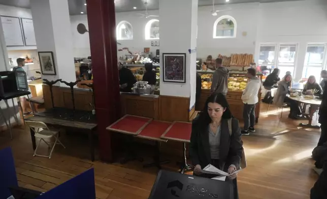 Zeena Karim, foreground, votes at La Boulangerie in San Francisco, Tuesday, Nov. 5, 2024. (AP Photo/Jeff Chiu)