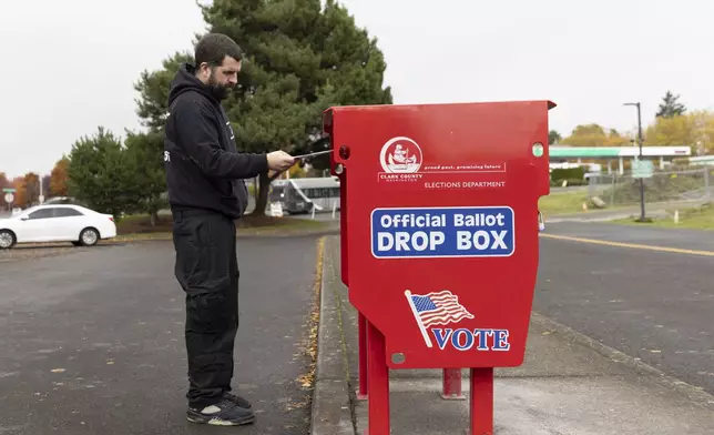 A voter drops his ballot at the Fisher's Landing Transit Center ballot drop box, which was replaced after a fire caused by an incendiary device, in Vancouver, Wash., Tuesday, Nov. 5, 2024. (AP Photo/Amanda Loman)