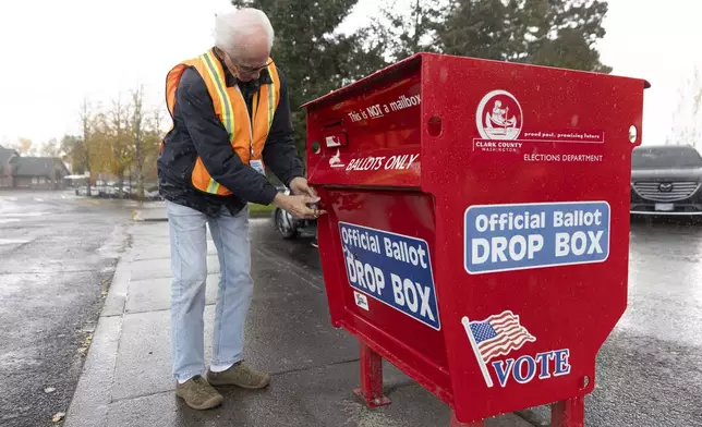 An election worker unlocks the Fisher's Landing Transit Center ballot drop box, which was replaced after a fire caused by an incendiary device, to collect ballots in Vancouver, Wash., Tuesday, Nov. 5, 2024. (AP Photo/Amanda Loman)