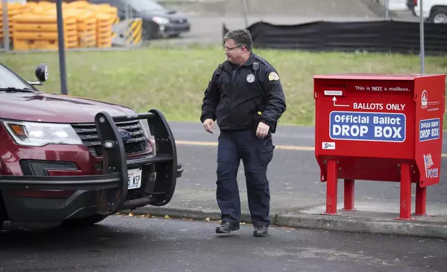 A Washington State Trooper patrols the Fisher's Landing Transit Center ballot drop box, which was replaced after a fire caused by an incendiary device, in Vancouver, Wash., Tuesday, Nov. 5, 2024. (AP Photo/Amanda Loman)