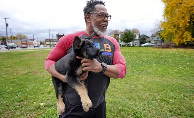 Small business owner Michael Hooks takes a break from working in the kitchen of his catering business to play with his dog in Erie, Pa. Friday, Nov. 1, 2024. (AP Photo/Gene J. Puskar)