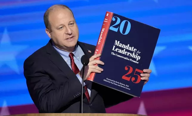 FILE - Colorado Gov. Jared Polis holds up a copy of Project 2025 as he speaks during the Democratic National Convention Aug. 21, 2024, in Chicago. (AP Photo/J. Scott Applewhite, File)