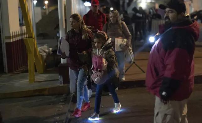 Migrants from Cuba pass a Mexican customs checkpoint as they make their way across the border for their appointments to legally apply for asylum in the United States, Tuesday, Nov. 5, 2024, in Tijuana, Mexico. (AP Photo/Gregory Bull)