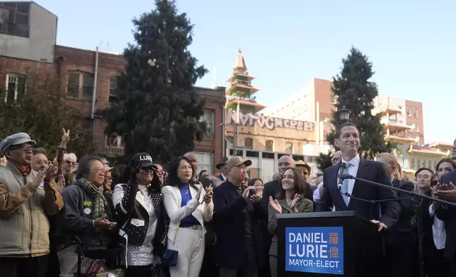 San Francisco mayoral candidate Daniel Lurie, foreground right, speaks at a news conference next to his wife in San Francisco, Friday, Nov. 8, 2024. (AP Photo/Jeff Chiu)