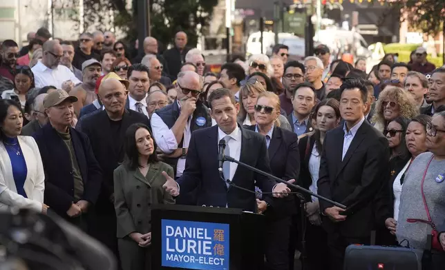 Daniel Lurie, center, speaks at a news conference accompanied by his wife, Becca Prowda, center left, in San Francisco, Friday, Nov. 8, 2024. (AP Photo/Jeff Chiu)