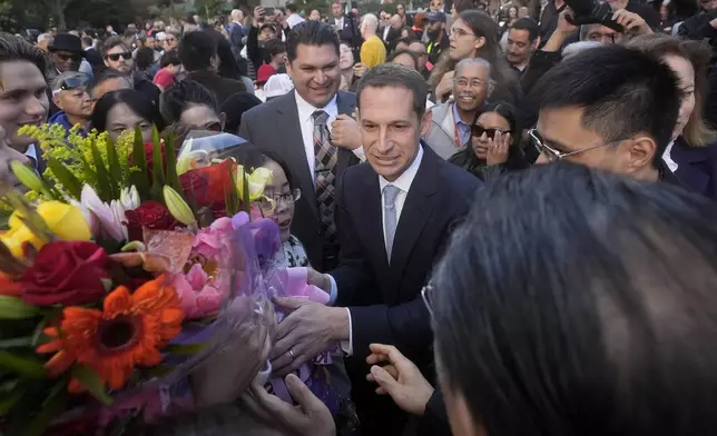 San Francisco mayoral candidate Daniel Lurie, middle, is greeted by supporters after speaking at a news conference in San Francisco, Friday, Nov. 8, 2024. (AP Photo/Jeff Chiu)