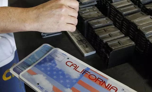 FILE - An inmate selects the letters and numbers to be used to make a specialty license plate by Prison Industries at Folsom State Prison, May 15, 2012, in Folsom, Calif.(AP Photo/Rich Pedroncelli, File)