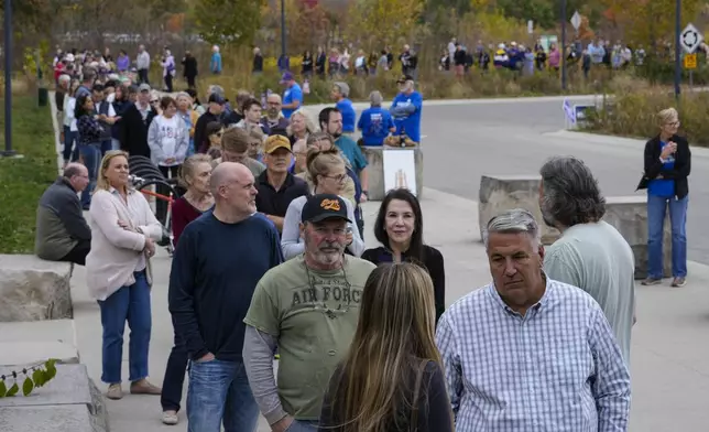 Voters line up to vote as a early voting location opened in Carmel, Ind., Wednesday, Oct. 23, 2024. (AP Photo/Michael Conroy)