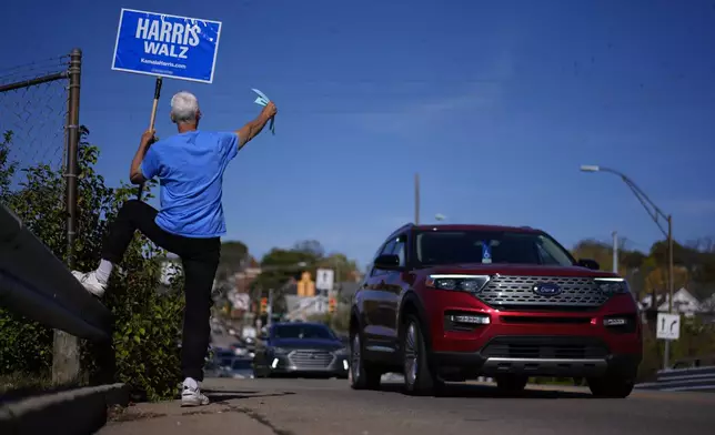 A supporter of Democratic presidential nominee Vice President Kamala Harris hands out sample ballots as cars arrive for early voting at the Hamilton County Board of Elections, Saturday, Nov. 2, 2024, in Cincinnati. (AP Photo/Carolyn Kaster)