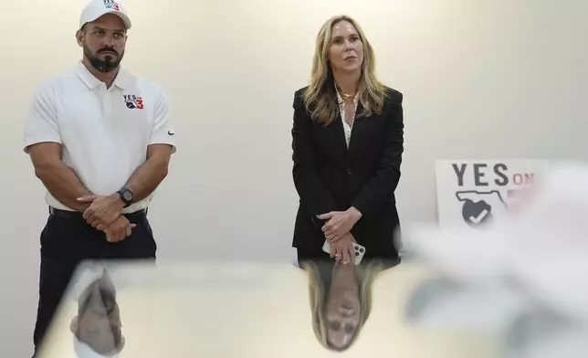 Trulieve CEO Kim Rivers, center, is reflected in a display case while participating in a discussion on the medical marijuana company's safety standards at an event in support of Amendment 3, which would legalize the recreational use of pot in Florida, Wednesday, Oct. 23, 2024, at a Trulieve medical cannabis dispensary in Hallendale Beach, Fla. (AP Photo/Rebecca Blackwell)