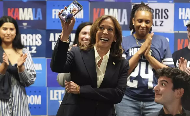 Democratic presidential nominee Vice President Kamala Harris holds up a phone as she phone banks with volunteers at the DNC headquarters on Election Day, Tuesday, Nov. 5, 2024, in Washington. (AP Photo/Jacquelyn Martin)